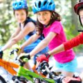 tri deti s prilbami na detskych bicykloch